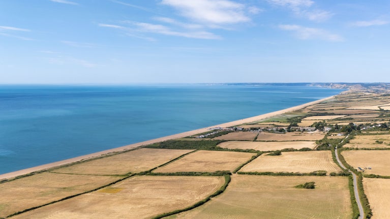 An aerial view of the countryside and coast surrounding Labour in Vain Cottage, including Chesil Beach